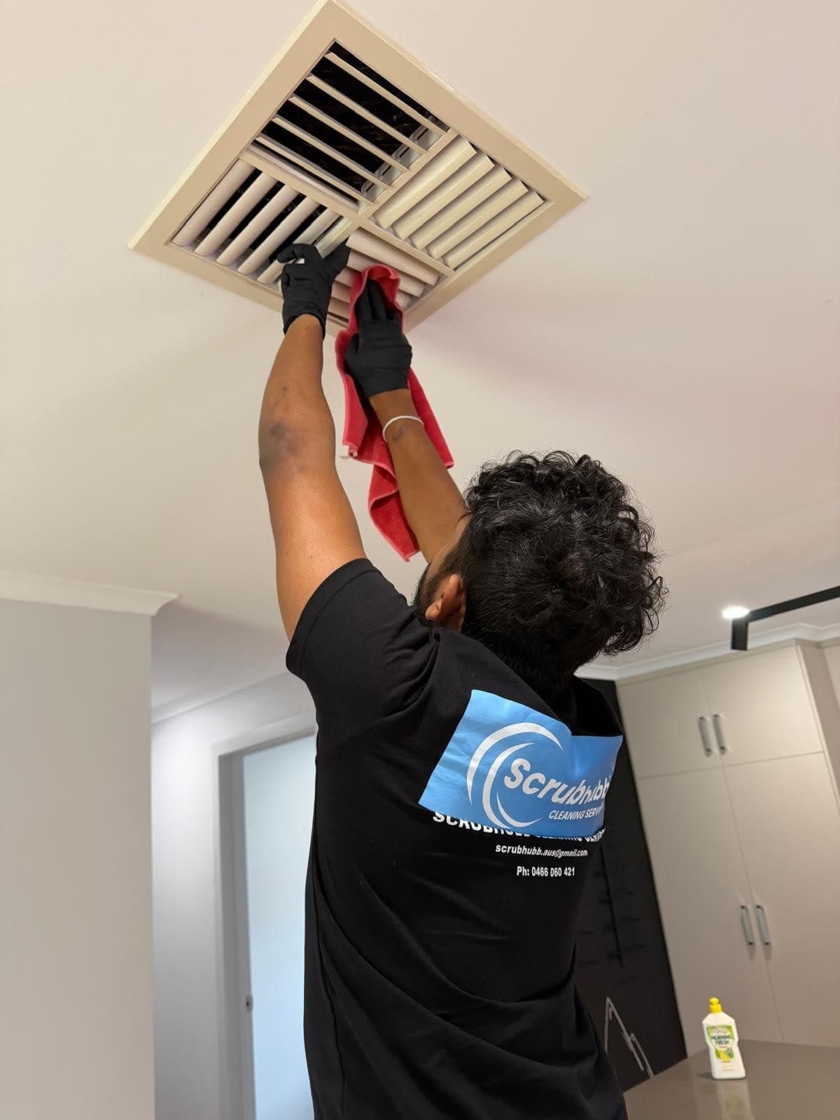 Scrubhubb cleaner in uniform cleaning ceiling air vent - Adelaide